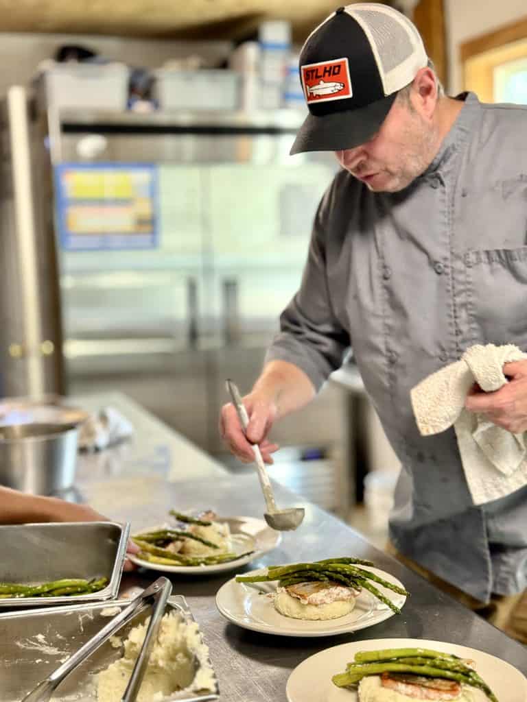 Chef plates salmon and asparagus.