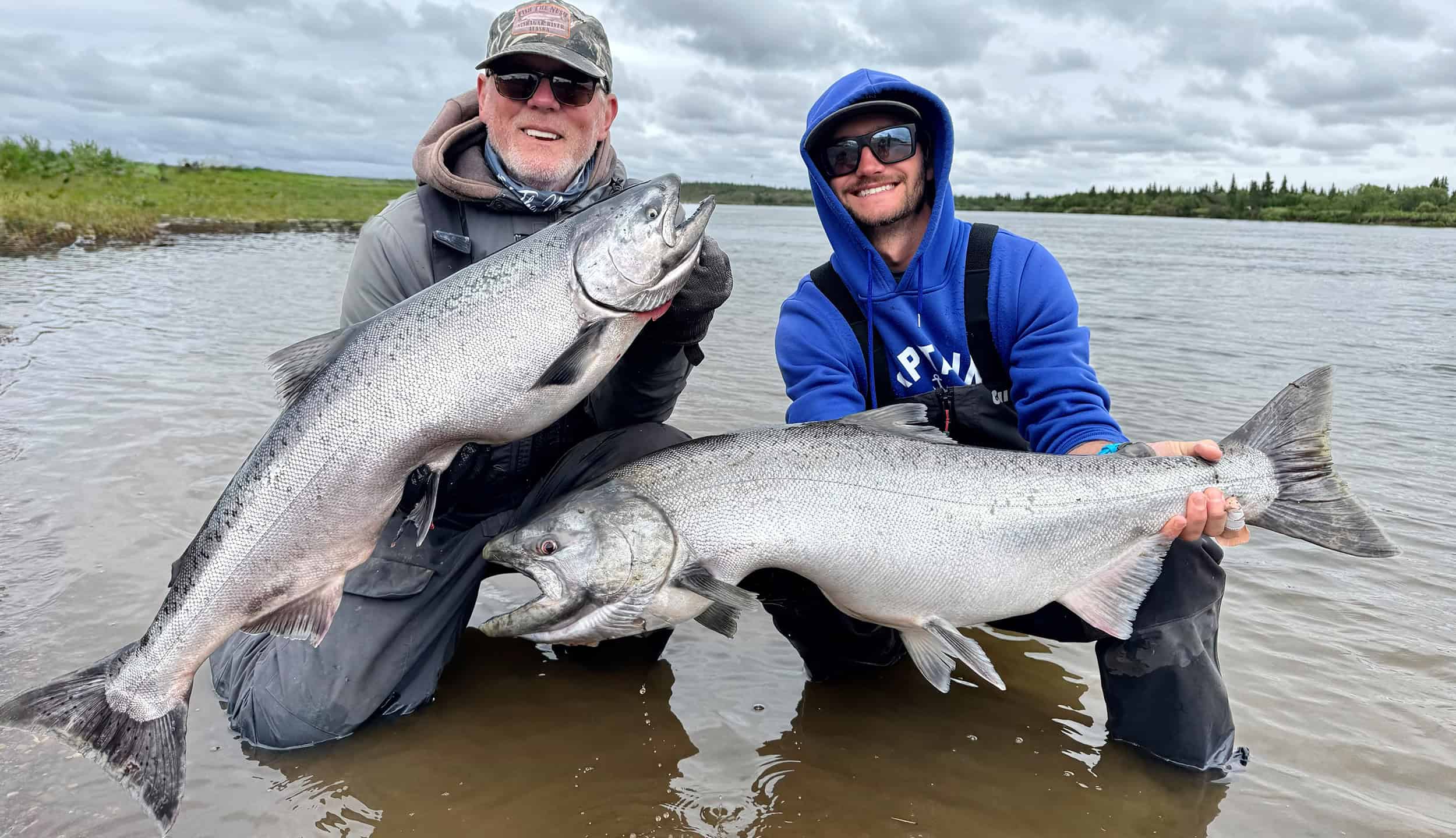 Two men holding large salmon.